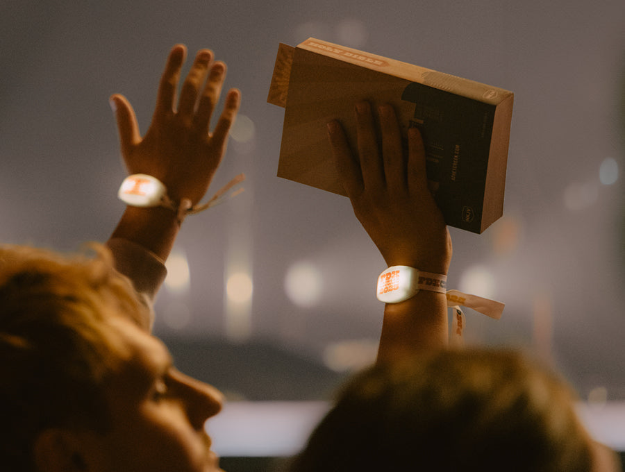 A crowd of people with two hands in the air, one holding a Bible. 