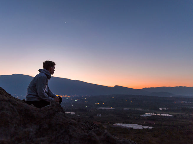 Man on a hillside looking at the sunset