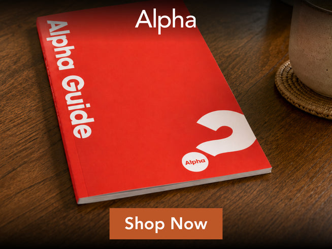 Red book titled 'Alpha Guide' with a white question mark on a wooden surface, featuring an 'Alpha' logo.
