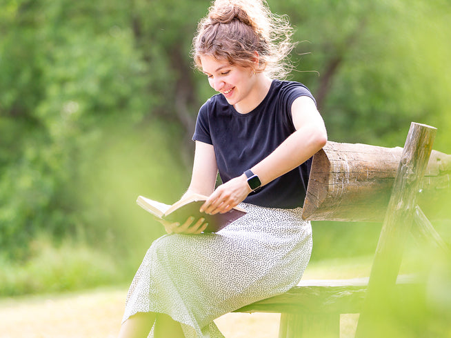 Woman reading a book on a bench in a park