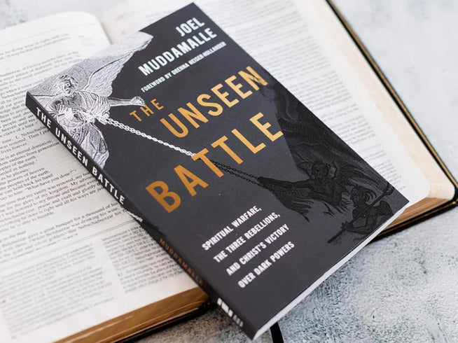 Book titled 'The Unseen Battle' by Joel Maddamale on an open book