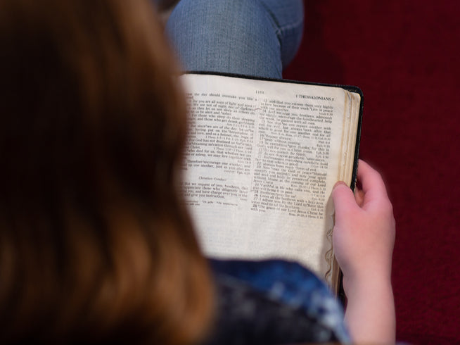 Person reading an open book with a blurred background