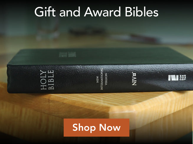 A black Holy Bible with white lettering rests on a light wood surface, with promotional text reading 'Gift and Award Bibles' at the top and an orange 'Shop Now' button at the bottom.