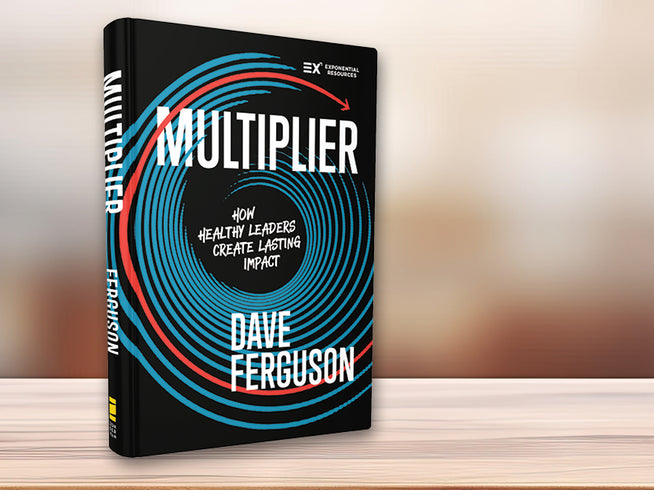 Book titled 'Multiplier' by Dave Ferguson on a wooden surface with a blurred background