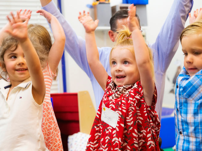 Children with raised hands in a classroom setting