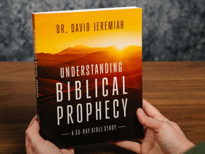 Book titled 'Understanding Biblical Prophecy' by Dr. David Jeremiah held by a person on a wooden surface.