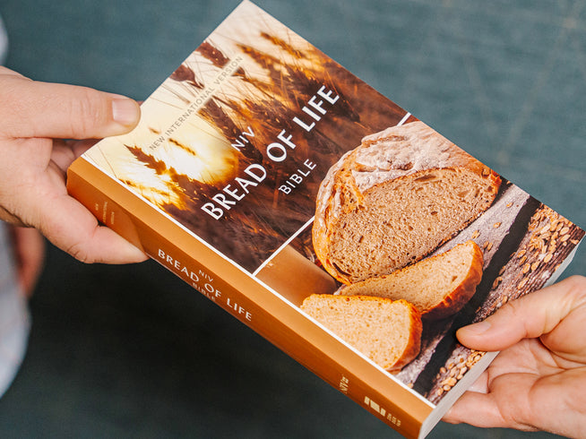 Book titled 'Bread of Life' held by two hands with a blurred background