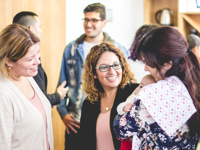 Three women socializing, one holding a baby