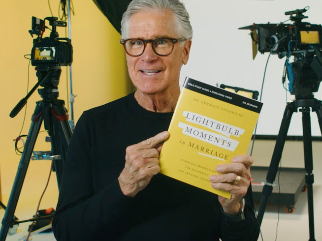 Author holding Lightbulb Moments in Marriage Bible Study Guide in front of a video production setup