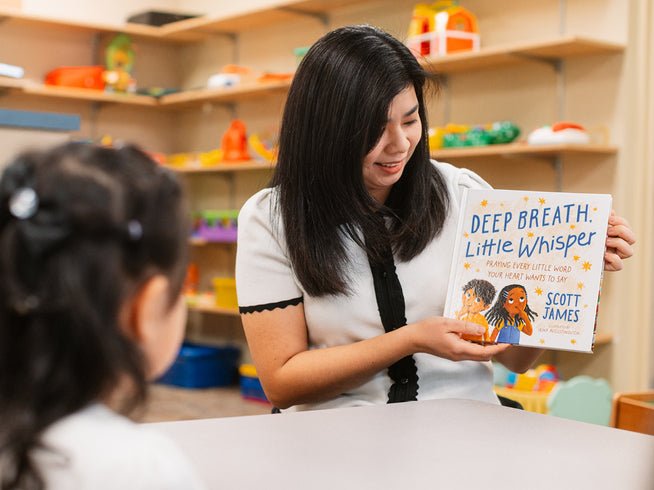 Teacher reading Deep Breath, Little Whisper by Scott James to a young child in a classroom