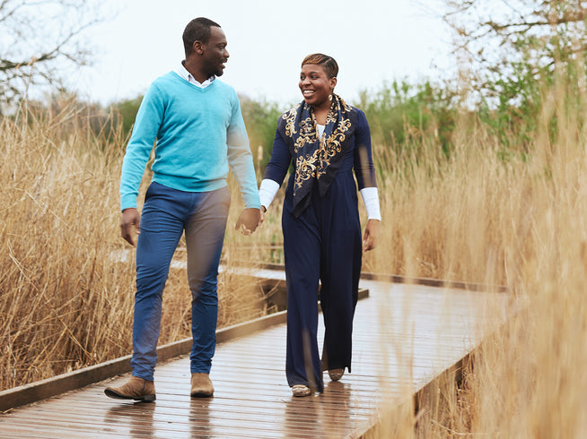 Smiling happy couple walking hand in hand on a bridge