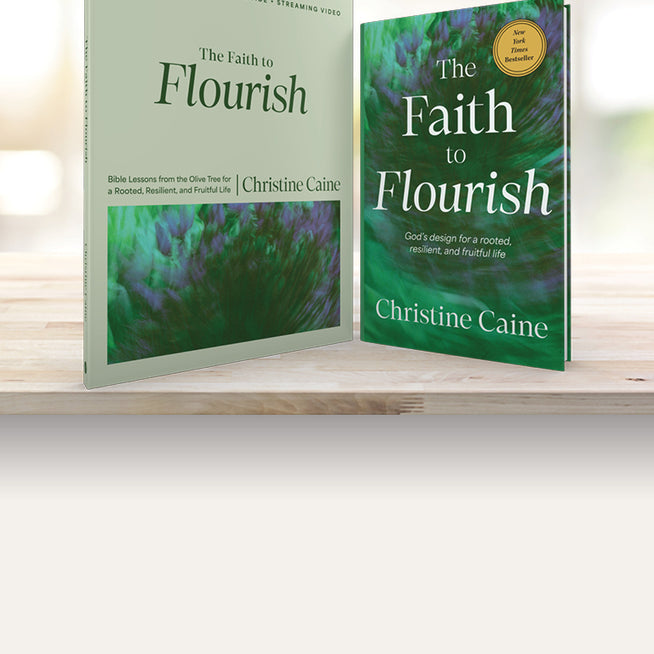 Two copies of 'The Faith to Flourish' by Christine Caine on a wooden surface with a blurred background.
