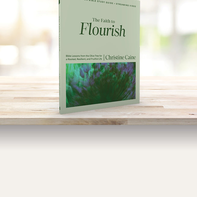 Book titled 'The Faith to Flourish' by Christine Caine on a wooden surface with a blurred background