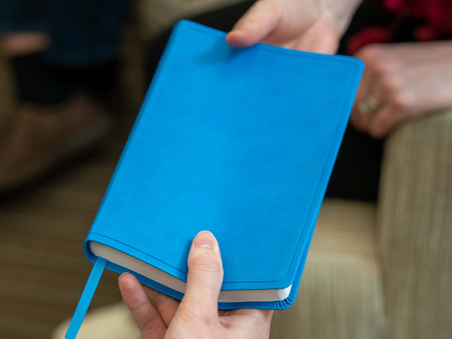 Person handing bible to another person