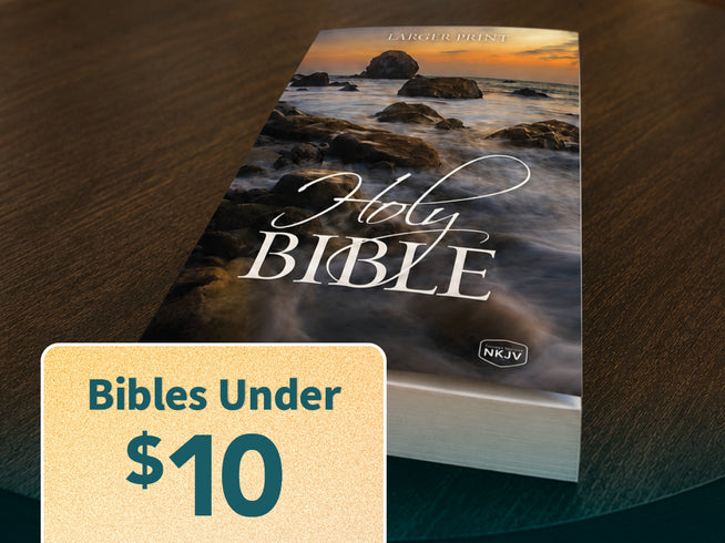 Holy Bible book cover displayed on a dark wooden surface, featuring a coastal sunset scene on the cover with large white 'Holy BIBLE' text and an NKJV logo. A promotional badge in the lower left reads 'Bibles Under $10'.
