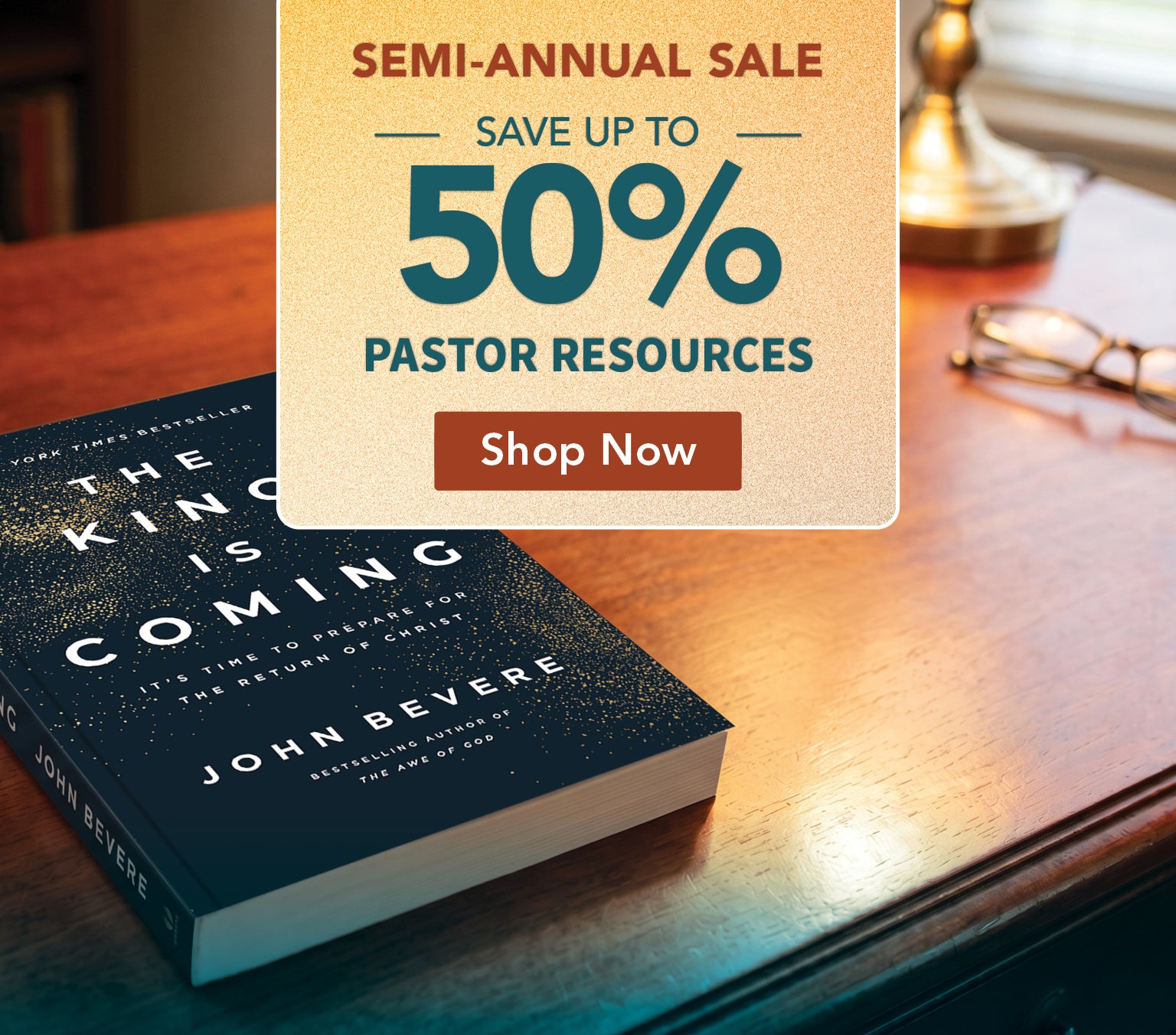 A promotional banner for John Bevera's book 'The King Is Coming' featuring a large sale overlay that reads 'Semi-Annual Sale Save Up To 50% Pastor Resources Shop Now' on a warm-toned wooden desk background.
