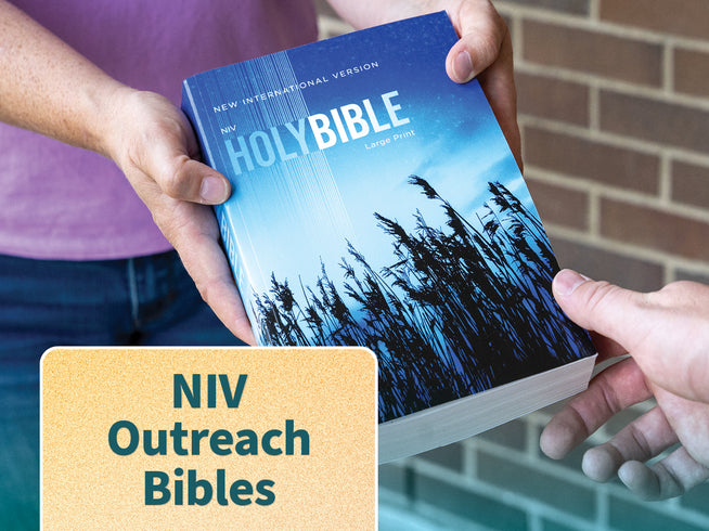 A person holding a copy of the NIV Holy Bible, with a text overlay in the bottom left corner reading 'NIV Outreach Bibles'. The book cover features a blue sky and dark grass silhouette design.